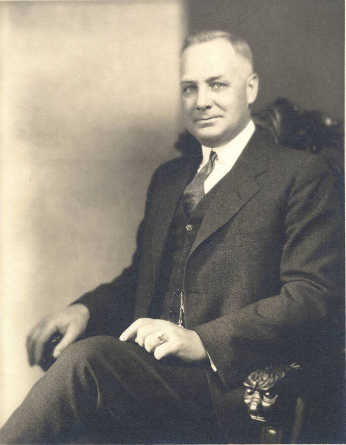 Portrait of middle-aged Frank B. Robinson wearing a three piece suit with pocket watch and sitting in an ornate chair with animals carved into the handles.