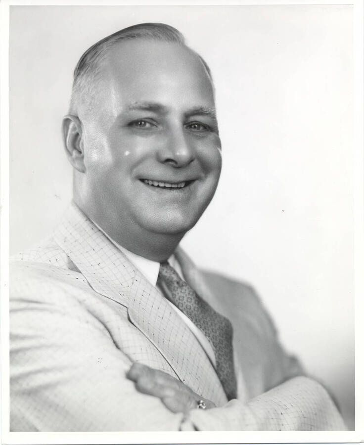Portrait of older Frank B. Robinson in a light colored suit and tie crossing his arms.
