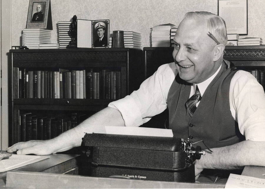 Photograph of Frank B. Robinson sitting at a desk behind his typewriter with a pencil behind his ear.