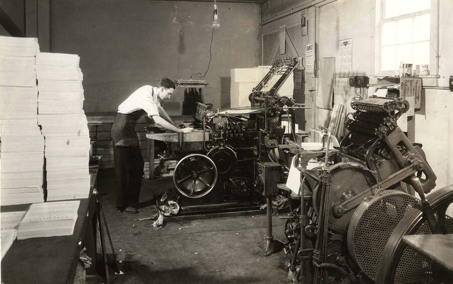 Photograph depicts a male Psychiana staff member leaning over an industrial printing press.