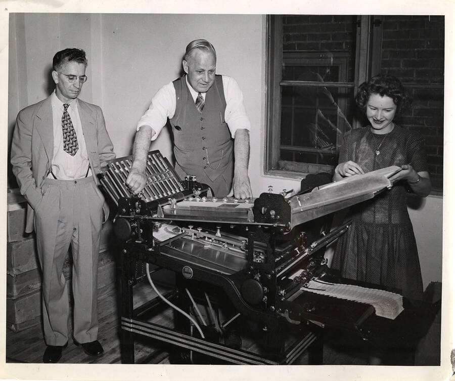 Photograph depicts (from left to right) W.W. DeBolt standing with his hands in his pockets, Frank B. Robinson with sleeves rolled up adjusting a sorter, and a female Psychiana Staff Member collecting materials as they leave the sorter.