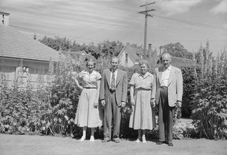 Photograph depicts the entire Robinson family, in Frank B. Robinson and Pearl Bey Robinson's older years, standing outside in front of a row of bushes.