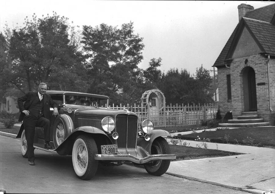 Photograph of Frank B. Robinson Posing with his Duesenberg Convertible Coupe in front of his home.