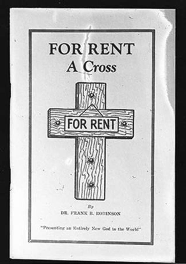 Negative photograph of book cover of Frank B. Robinson's book with a cross and sign reading 'FOR RENT' nailed to the front and the quote 'Presenting an Entirely New God to the World' at the  bottom.