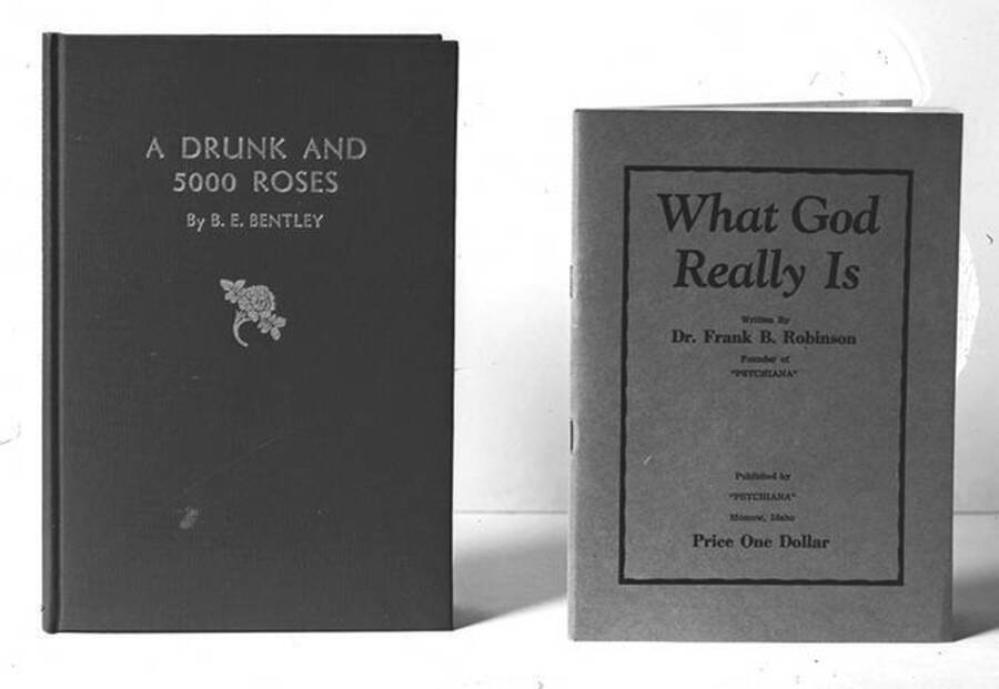 Negative photograph of the cover of Frank B. Robinson's pamphlet What God Really Is, which includes only text of the title, author name, price, and publishing press Psychiana, Inc. The pamphlet appears side by side with the cover of B.E. Bentley's hardback book, which includes text and the picture of a flower.