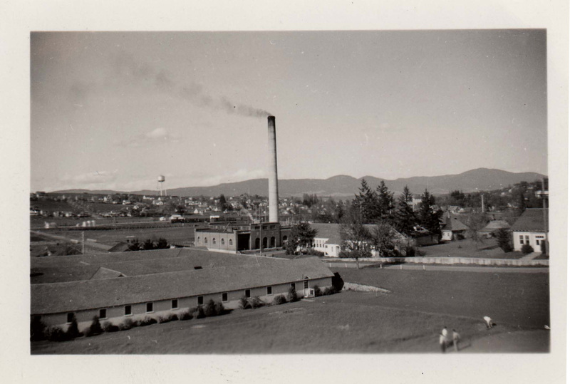 Power Plant (Center), dormitory and field in foreground; residential areas, water tank, and trees in the background.