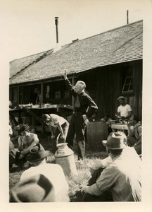 Dwights Jeffers, Dean of the Forestry school, standing with one arm raised up, in front of students sitting on the ground.