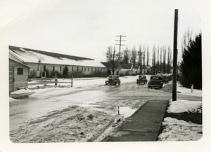 Cars parked along sidewalks and driving down snow covered roads in front of the Idaho Club dormitory.