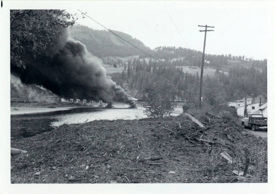 A photograph of Bridge 50.1 on the Camas Prairie Railroad next to the Kamiah Mine. Smoke billows from a fire on the railroad bridge.
