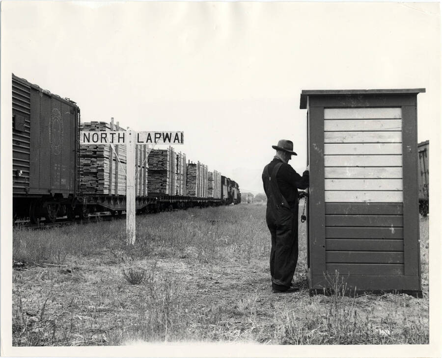 A photograph of the train conductor for train #662 phoning the dispatcher to let him know he is going to do some work in North Lapwai, forcing the train engines to stop for him.