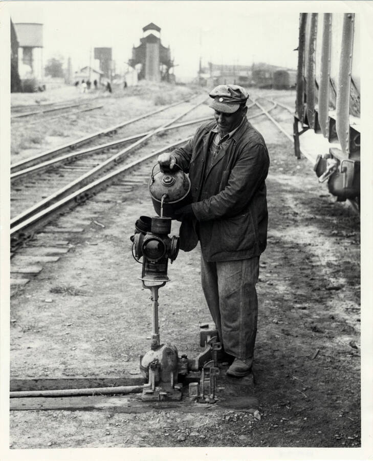 A section man filling a switch lamp with oil in the engine terminal of the East Lewiston Train Yard.