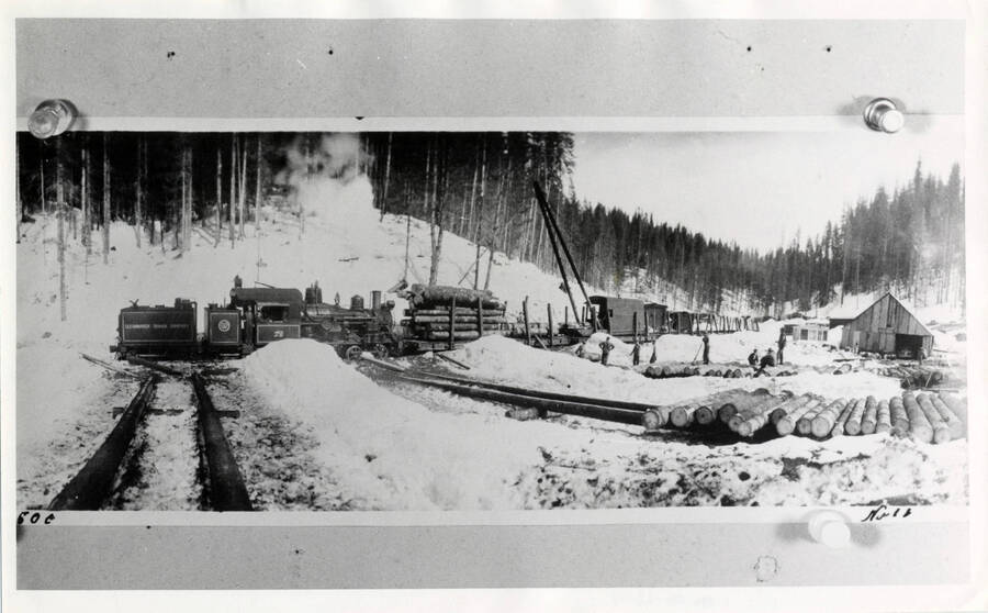 A photograph of a Clearwater Timber Co. Train Engine moving through Potlatch, ID in the snow.