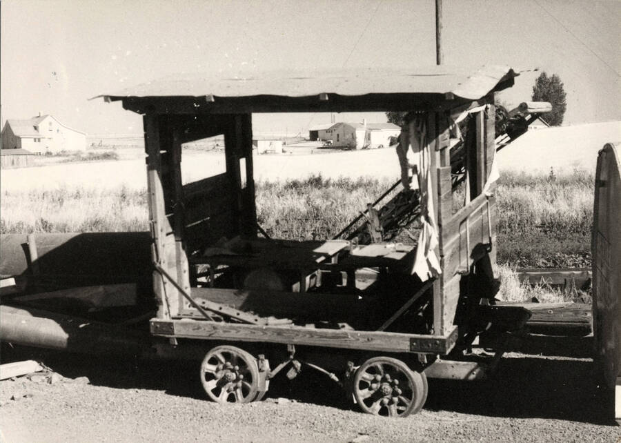 A photograph of 'a retired maintenance car sit[ting] in the wheat fields in Nez Perce, Idaho in the summer of 1973. Its years of service is at an end. The boxy, tin roof canopy protected the track workers from the hot relentless sun of the Camas Prairie wheat fields.'