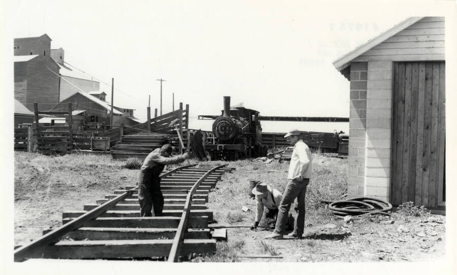 A photograph of three men in the process of building a track for Nez Perce & Idaho Train Engine no. 4 to be moved to the 4-spot for transport to Lewiston. Herb Banks had charge of conditioning the engine for movement to Lewiston.