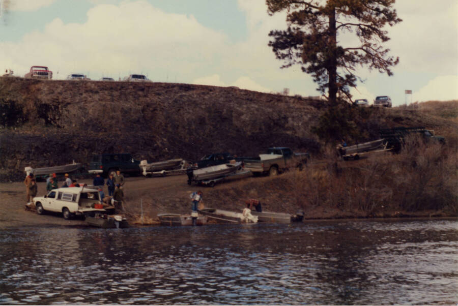 A color photograph of what appears to be a boat launch where people are launching their aluminium boats with outboard motors.