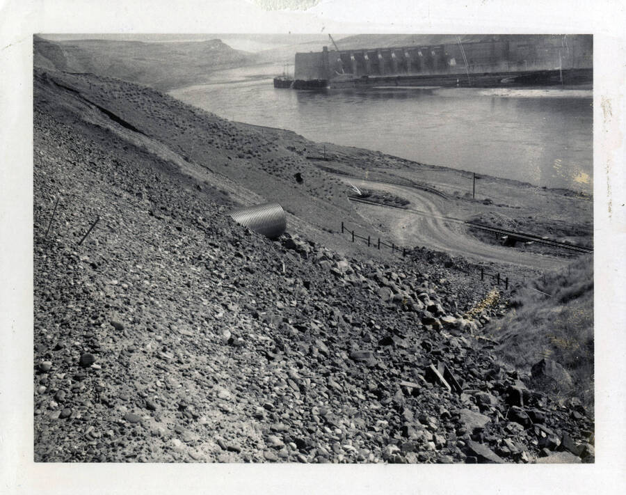 A photograph of culvert outlet protection from the southeast in Walla Walla. The photo features the river in the background, as well as some sort of damn or water resource management plant along the river.
