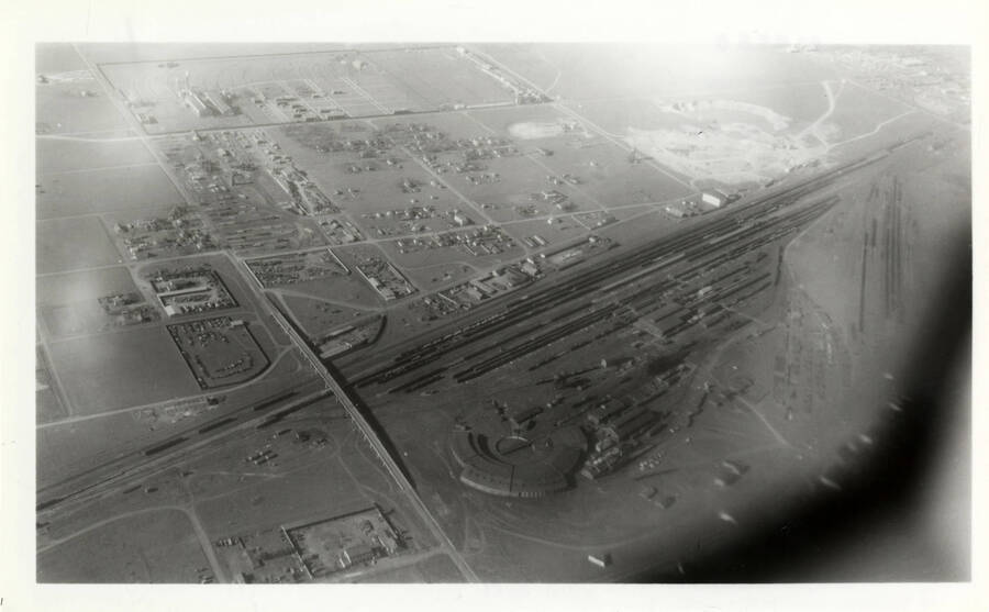 A photograph of the Parkwater Roundhouse as see from the window of an airplane. An excerpt from Ron Nixon: 'Remember my remark about Joe Lux suing us. So maybe some of these remarks may be unacceptable. Anyway I knew Joe pretty well as I was the go-between with him and NP during negotiations to retrieve 684. So after the deal was closed I asked him to be sure to let me know when the engine was to be moved Nez Perce to Craigmont so as to get pictures. Time went by and I heard nothing from him. He lived in Spokane so it would have been a simple city phone call. I called him a couple of times and he said 'not yet' or words to that effect. Then late one night when I was working with the CP operator at Lewiston he mentioned that CP men were going to Nez Perce to get the 684 moving. So I called Joe and he said, 'Oh yes. They plan on moving it at eight in the morning.' !!!! I had no automobile at the time but had access to NP company cars. NP said I could use one but would have to get it back the same night, which of course was impossible. I checked with the bus companies and there was no bus I could get to Lewiston before the next morning. So as a last resort I called the airport and found that there was a plan for Lewiston at six in the morning. After some hectic getting-ready, I was on the plane and took this picture of the Parkwater roundhouse as we went over it. A little dull as I shot it through the window and it was real early in the morning. Got to Lewiston in time to catch the CP going to Craigmont. Then I had to bum a ride to Nez Perce on the Nez Perce truck. They were already working on 684 when I got there. You already have my first pictures.'