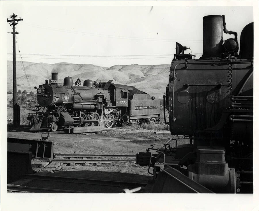 A photograph of a few stationary train engines resting near the turntable in the Lewiston Train Yard.