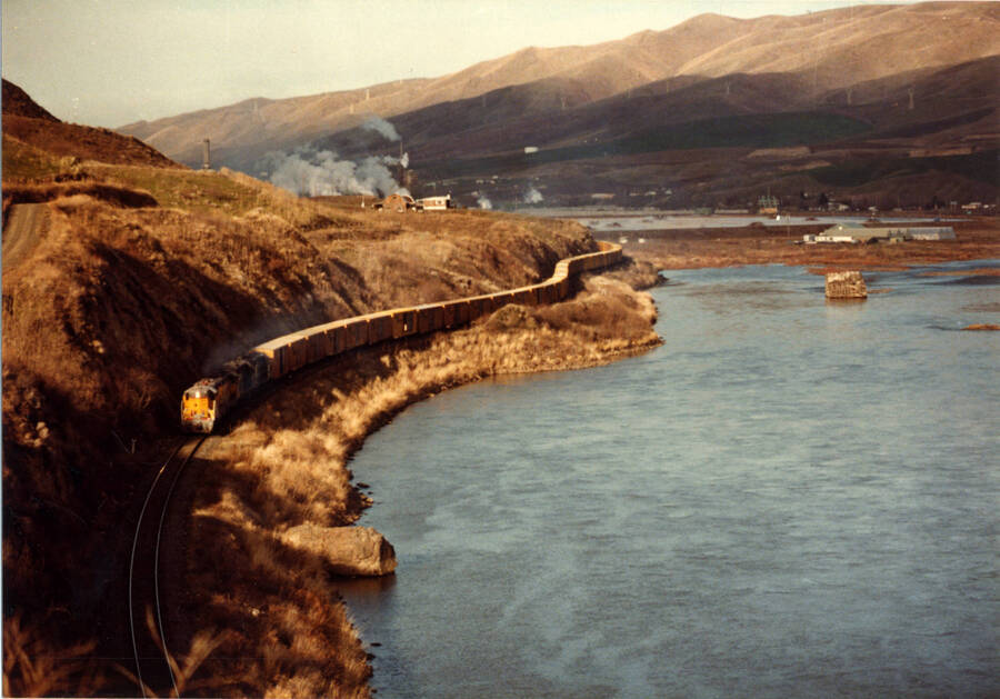 A photograph of Grangeville Local loaded down with extra rail box borders leaving Forebay. The R-Box cars to be stored on the Nezperce Railroad.