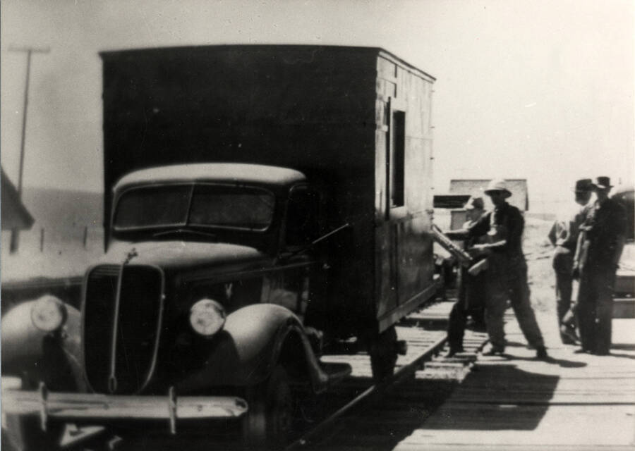 A photograph of a 1936 Ford truck/bus that hauled mail and passengers between Nez Perce and Craigmont until 1946 when all passenger service was discontinued. In this scene the rail mounted truck receives the morning mail in preparation for its 13.5 mile trip to Craigmont and a connection with the Camas Prairie railroad to Lewiston, Idaho.