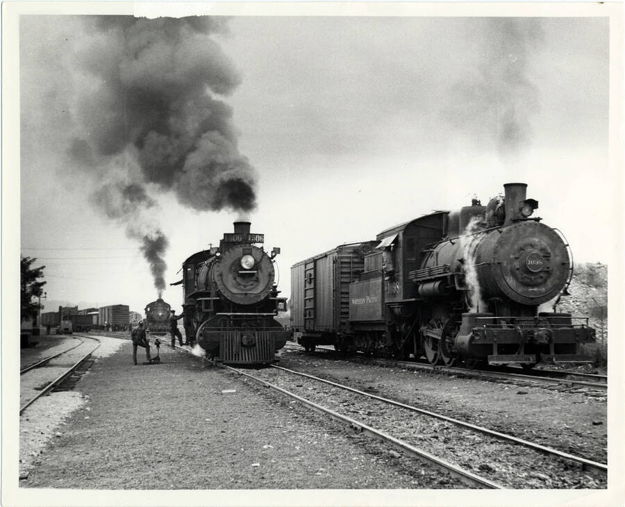 A photograph of train engine #4922 and train engine #1098 being examined and worked on in the train yard, while a third engine (#1506) prepares to carry freight to Grangeville.