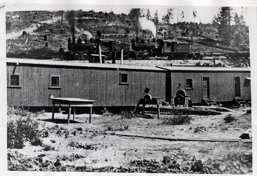 Logging camp in the 1940's pictured with a locomotive in the background.