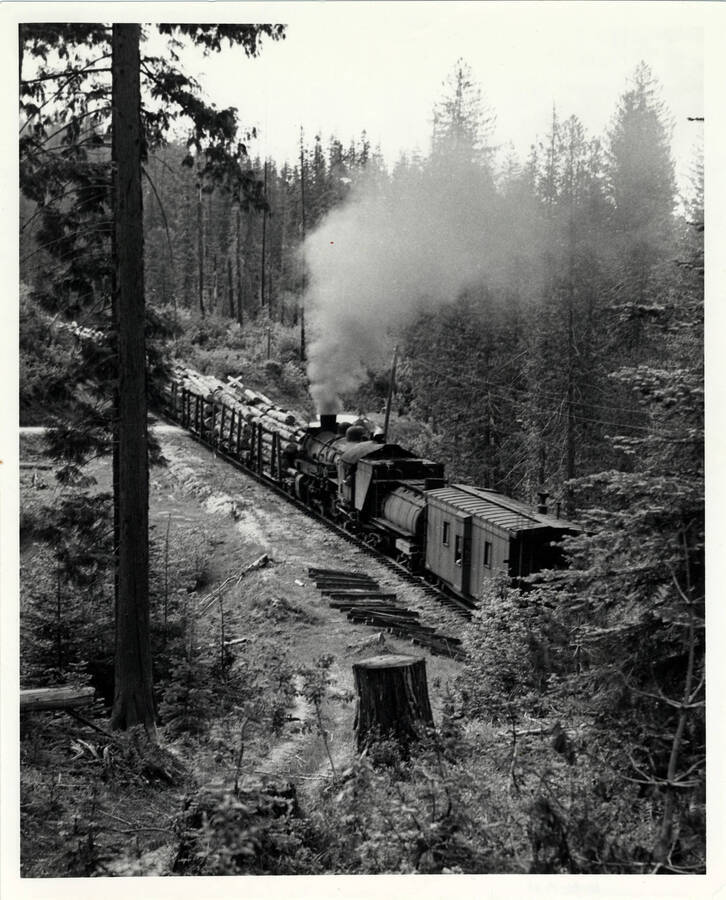 A photograph of train engine '#2711 hugging mightily at the rear of Extra 2504 West, the Headquarters logger in Deer Creek, Idaho.'