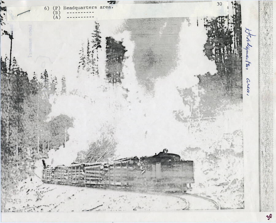 A paper copy of a photograph of a freight train engine carrying a lumber load near the Headquarters Area.