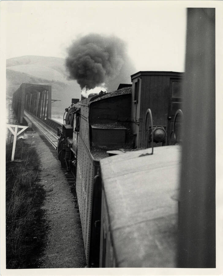 A photograph of freight train #662 about to cross a metal railway bridge while headed for Spokane from Arrow, ID.