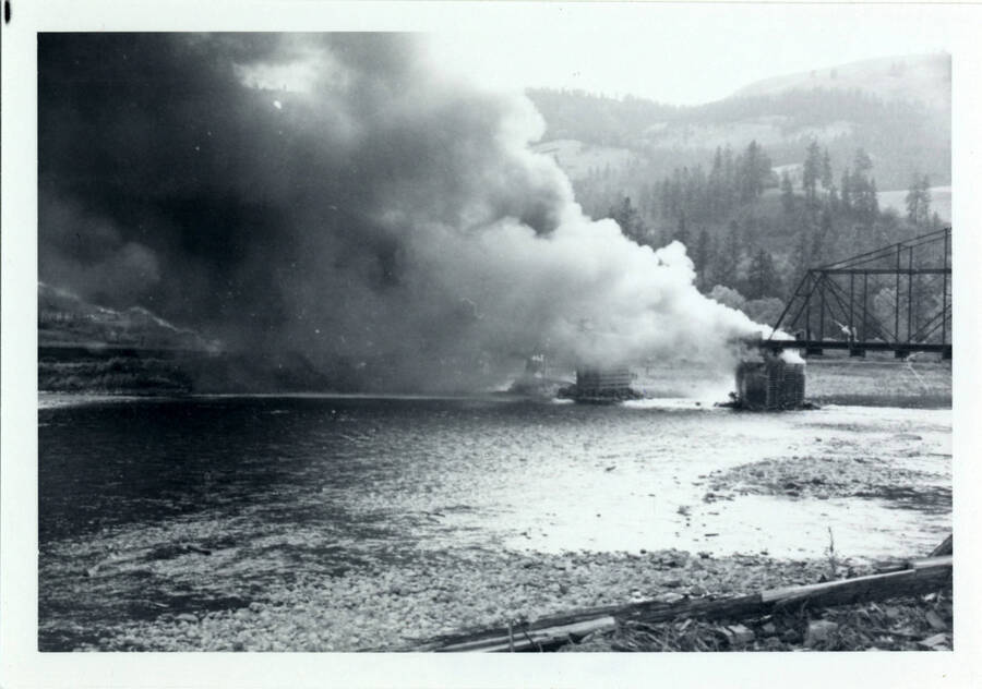 A photograph of Bridge 50.1 on the Camas Prairie Railroad next to the Kamiah Mine. Smoke billows from a fire on the railroad bridge.