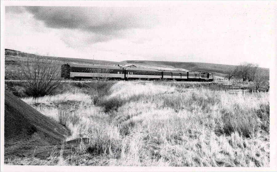 A photograph of Passenger Train 311 moving through the Pullman Junction. Details from the creator about the train: 'Substitute standard equipment on train 311. Since no more RPO, only baggage car is used. Very unusual is newer mainline North Coast Limited coach on rear. Note 'Y' lead track in front of first coach.'