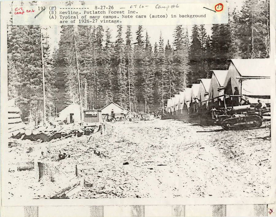 A paper copy of a photograph of Camp #6 of Potlatch Forest Inc. in Headquarters, Idaho. Typical of many camps. Note cars (autos) in background are of 1926-27 vintage. Revling.