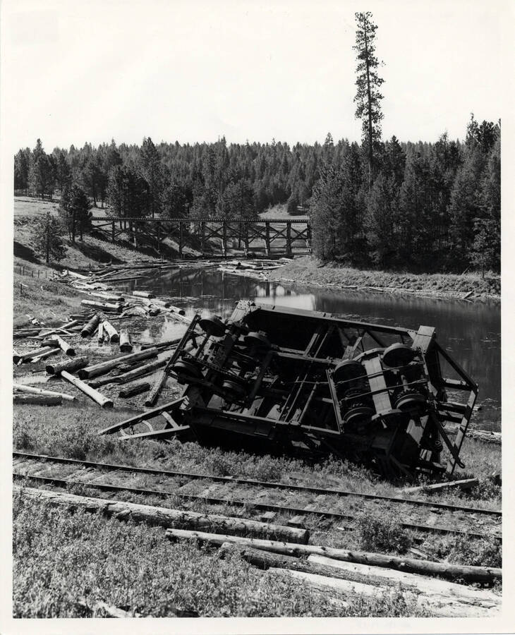 A photograph of a log jammer, tipped over after an attempt at lifting too heavy a log, was not righted because the woods track in the background was abandoned to trucks.