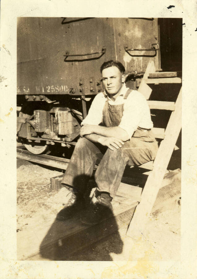 A photograph of Earl Cash sitting on the steps up to a train car.