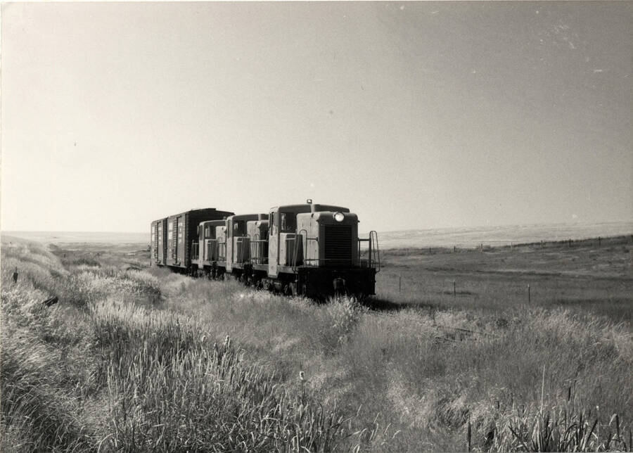 A photograph of the three electric train engines of the Nez Perce Railroad. These 'make up the operating roster of the Nez Perce Railroad. No.'s 7114-7115-7116 were acquired from an air force base in Utah in 1973 for $30,000.00 The flame red/orange color is possibly the brightest diesel engines in the country.