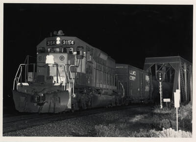 Union Pacific freight train No. 3154 passing over a bridge at night.