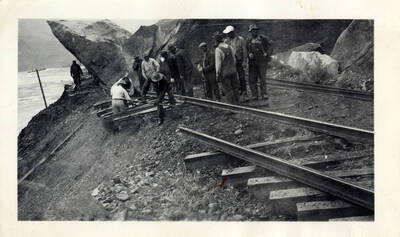 Railroad workers cleaning up a granite rock slide with construction vehicles.