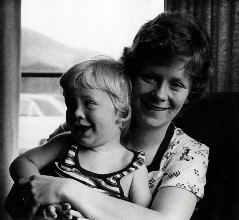 Photograph of Sonja Christine Clyne sitting, smiling at the camera with a child on her lap.
