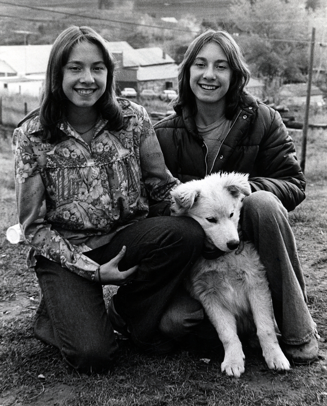 Photograph of Tami Lee McKinney & Trudi Lynn McKinney outside, smiling at the camera, with a dog.