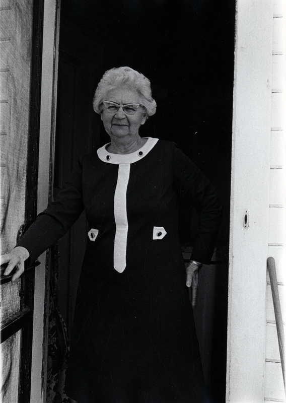Photograph of Alpha Procunier standing in a doorway, smiling at the camera.