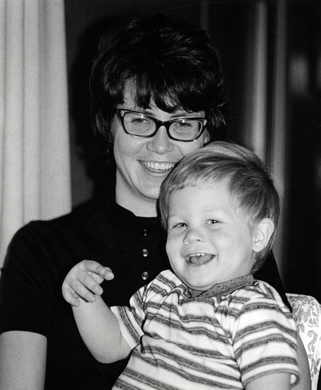 Photograph of Cathy Petrie seated, smiling at the camera, with a child on her lap.