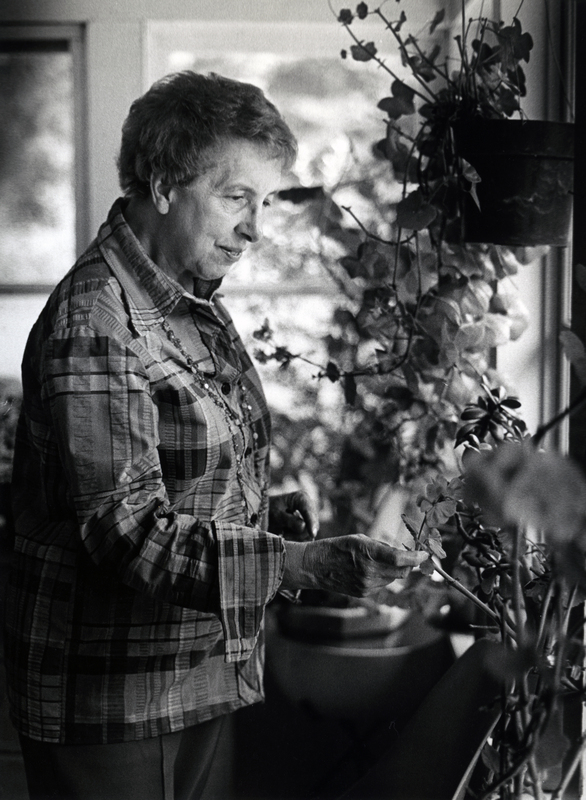 Photograph of Muriel Margaret Siegel standing, looking at house plants.