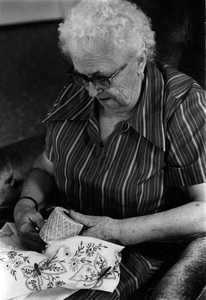 Photograph of Ella Lillian Olson looking down at an embroidery project.