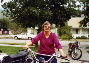 Color photograph of Myra Jeanne Stark outside, sitting on a motorcycle.