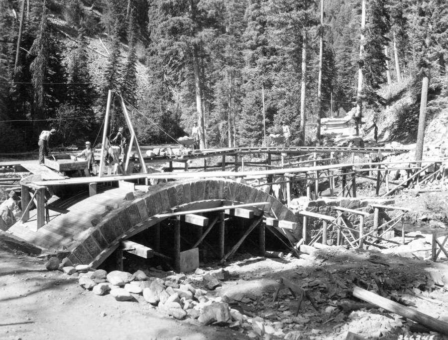 Stone arch bridge at Deep Creek under construction by CCC labor, Deep Creek, Bitterroot National Forest, Idaho, Swan, K. D., 1938-08-01
