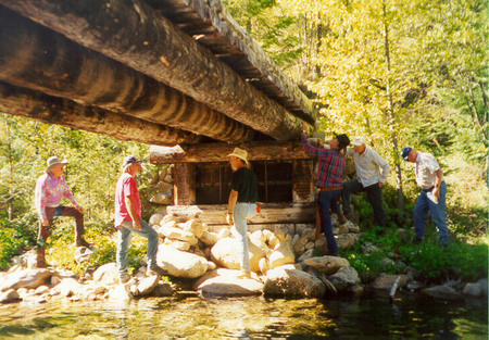 Forest Rangers examining the Goat Creek bridge in 1999. This bridge is a girder-span style bridge made from indigenous materials.