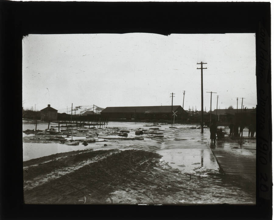 Flooding in Moscow, Idaho during the spring. People standing in background. The glass slide reads: 'Moscow Idaho, Spring 1910.'