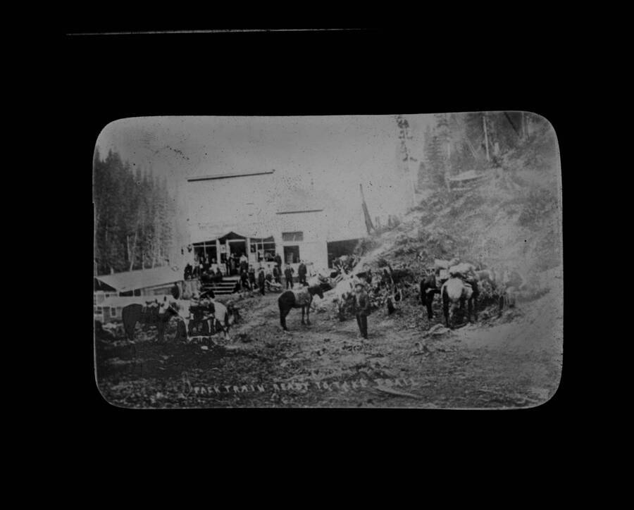 The glass slide reads: 'Firefighters at Avery, Ida. All these men lost their lives.' A caption is also also superimposed on the image. It reads: 'Pack train ready to take trail.'