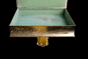 Close up detail of one long edge of object, featuring an etched scene of a miner with pack mules. Underside of lock and velvet interior of box also pictured. 