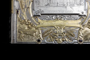 Close up detail of jewelry box cover corner featuring golden relief of logs and an ax.